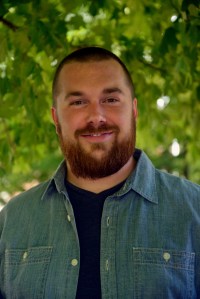A picture of the author in front of green blurred leafy background